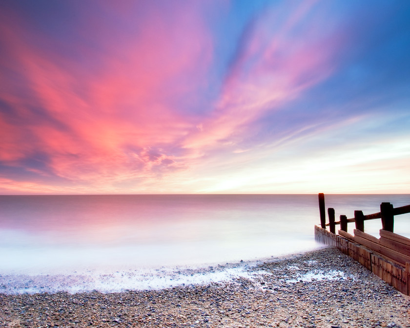 sunrise over sea and beach at dawn-1 
 pink sky at dawn over calm sea and beach 
 Keywords: Beach, Groynes, Mist, Reflections, Rocks, Sea, Suffolk, Sunrise, Tony Pick, atmospheric, dawn, light, movement, nautical, pink, sky, smoke, structure, tide, waves